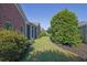 Landscaped backyard featuring lush green lawn, mature trees, and a brick home with screened porch at 1550 Rolling View Dr, Cumming, GA 30040