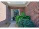 Close-up of a brick entryway featuring a black front door with sidelight, framed by lush green shrubbery at 1550 Rolling View Dr, Cumming, GA 30040