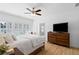 Bright bedroom featuring hardwood floors, ceiling fan, dresser, and large window with shutter blinds at 6820 Colfax Ave, Cumming, GA 30040