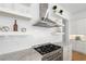 Close-up of kitchen featuring stainless steel range hood and cooktop with white backsplash at 6820 Colfax Ave, Cumming, GA 30040
