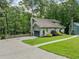 View of a two-story home with a driveway, green lawn, and mature trees, showcasing its suburban setting at 162 Nouveau Sw Ct, Lilburn, GA 30047