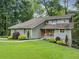 Charming two-story home featuring a manicured lawn, vibrant landscaping, and a welcoming red front door at 162 Nouveau Sw Ct, Lilburn, GA 30047