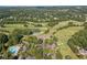 Aerial view of a lush golf course with swimming pool, clubhouse, and surrounding wooded area at 6455 Darely Ct, Cumming, GA 30040