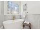 Freestanding tub near decorative window and marble style tiling creates a relaxing spa atmosphere at 6455 Darely Ct, Cumming, GA 30040