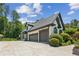 Elegant home exterior featuring a three-car garage, brick facade, and manicured landscaping at 6455 Darely Ct, Cumming, GA 30040