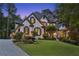 Elegant two-story home with a well-manicured lawn and beautiful landscaping at twilight at 6455 Darely Ct, Cumming, GA 30040