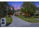 Charming home with a curved driveway, lush landscaping, and manicured lawn at dusk at 6455 Darely Ct, Cumming, GA 30040