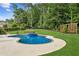A beautiful kidney-shaped pool and spa are surrounded by manicured lawn and mature trees at 6455 Darely Ct, Cumming, GA 30040