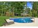 A beautiful kidney-shaped pool and spa are surrounded by manicured lawn and a lounge chair at 6455 Darely Ct, Cumming, GA 30040