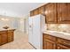 Bright kitchen area with white refrigerator, wood cabinets, and tile floors, opening to another room at 786 Mitsy Pt, Marietta, GA 30068
