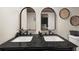 Bathroom vanity with double sinks, dark countertop, arched mirrors and decor at 9025 Huntwood Ln, Riverdale, GA 30274