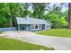 The beautiful, light blue home features a carport and a large driveway, surrounded by lush landscaping at 9025 Huntwood Ln, Riverdale, GA 30274