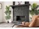Stone fireplace with dark mantle, flanked by palm trees, in the living room at 9025 Huntwood Ln, Riverdale, GA 30274