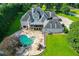 Aerial view of a large home and in-ground pool with stone patio, waterfall, hot tub, and water slide at 2871 Hosch Valley Rd, Buford, GA 30519