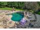 View of in-ground pool with stone patio, waterfall, hot tub, water slide, built-in grill, and lounge chairs at 2871 Hosch Valley Rd, Buford, GA 30519