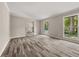 Sunlit living room with wood-look floors, large windows offering backyard views, and a view to a carpeted staircase at 5058 Rock Springs Rd, Lithonia, GA 30038