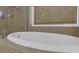 Close up on a luxurious soaking tub with tile surround, chrome fixtures, and natural light at 3123 Wolf Club Dr. Sw, Atlanta, GA 30349