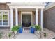 Inviting front door with white columns, potted plants, and lanterns creating a warm and welcoming entrance at 3123 Wolf Club Dr. Sw, Atlanta, GA 30349