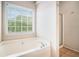 Bright bathroom features a soaking tub underneath a bright window at 55 Ashland Farm Rd, Oxford, GA 30054