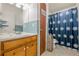 Bathroom with blue tile, wood vanity, and a shower with a patterned curtain at 5709 Center Hill Church Rd, Loganville, GA 30052