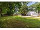 Expansive backyard featuring a lush lawn, a wood fence, mature trees, and an ample driveway leading to a detached garage at 2010 2Nd Ave, Decatur, GA 30032