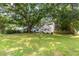 Spacious front lawn leads to a charming white home nestled under a mature tree, offering curb appeal at 2010 2Nd Ave, Decatur, GA 30032