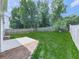 Backyard with a large grassy area, wooden fence, mature trees, and a small patio at 232 Oconee Way, Canton, GA 30114