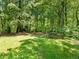 Backyard view of the lawn, surrounded by woods, with a gardening box and an old shed at 5020 Bayberry Dr, Cumming, GA 30040