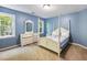 Bedroom featuring a four-poster bed, blue walls, dresser, carpet, and two windows for natural light at 5020 Bayberry Dr, Cumming, GA 30040