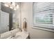 Half bath featuring white vanity, sink, mirror, and window at 740 Paris Dr, Lawrenceville, GA 30043