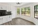 Bright eat-in kitchen area featuring hardwood style floors, white cabinets, a modern light fixture and plenty of natural light at 8649 Cedar Creek Rdg, Riverdale, GA 30274