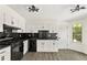 Bright kitchen featuring white cabinets, black countertops and backsplash, and modern lighting at 8649 Cedar Creek Rdg, Riverdale, GA 30274