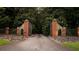 Private gated entrance featuring stone pillars, metal fencing, and tree-lined driveway at 114 Lees Lake Rd, Fayetteville, GA 30214
