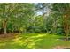 Lush backyard featuring a well-maintained lawn surrounded by mature trees and a classic black fence at 207 Lees Lake Rd, Fayetteville, GA 30214