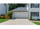A two-car garage with a white door is attached to this home featuring a large driveway at 2688 Beddington Way, Suwanee, GA 30024