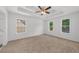 Large primary bedroom featuring a tray ceiling, multiple windows, and neutral carpet flooring at 2688 Beddington Way, Suwanee, GA 30024