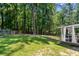 Green backyard featuring ample lawn space, mature trees, and a partial view of a covered deck at 830 The Cir, Lawrenceville, GA 30043