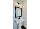 Close up of a half-bathroom featuring a pedestal sink, dark faucet and framed mirror with modern lighting at 12 Confederate Nw St, Cartersville, GA 30121