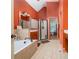 Bathroom featuring a tiled tub, glass shower, and orange accent walls with neutral tile at 2015 Buford Dam Rd, Buford, GA 30518