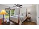 A comfortable bedroom featuring a four-poster bed, ceiling fan, and a window with a treelined view at 2660 Brentwood Estates Ct, Cumming, GA 30041