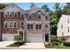 Brick and vinyl townhome boasts a two-car garage, black front door, and well-maintained landscaping at 3733 Chattahoochee Summit Se Dr # 7, Atlanta, GA 30339