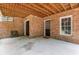 A covered patio area featuring brick walls, concrete flooring, and access doors, perfect for outdoor entertaining at 501 Highwater Pass, Canton, GA 30114