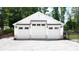 Modern three-car garage with white siding, dark trim, and gravel driveway at 604 Trinity Church Rd, Canton, GA 30115