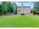 Large backyard with lush green grass, brick home exterior, play set, and patio at 360 Hannaford Dr, Roswell, GA 30075
