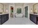 Bright bathroom features a soaking tub, glass shower, marble floors, and dual vanities with gold accents at 360 Hannaford Dr, Roswell, GA 30075