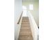 Carpeted staircase with white risers leads to upper level with natural light at 10770 Glenhurst Pass, Duluth, GA 30097