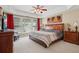 Primary bedroom with tray ceilings, ceiling fan, large windows with red curtains and furniture set at 25 Hampreston Court Ct, Johns Creek, GA 30022