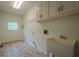 Clean laundry room includes utility sink, cabinets, shelving, and window for natural light at 2814 Tanner Lake Nw Trl, Marietta, GA 30064
