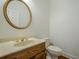 Stylish powder room boasts wood vanity, round mirror, gold hardware, and classic toilet at 2814 Tanner Lake Nw Trl, Marietta, GA 30064