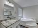 Bright bathroom with a garden tub, vanity with granite countertop, and wood-look flooring at 3573 Plantation Pl, Loganville, GA 30052